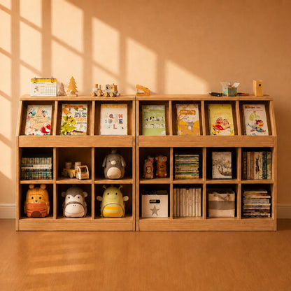 A light natural wood children's bookshelf with multiple cubbies, styled with books, plush toys, and small decorative items, set against a warm beige wall with soft window-shadow lighting.