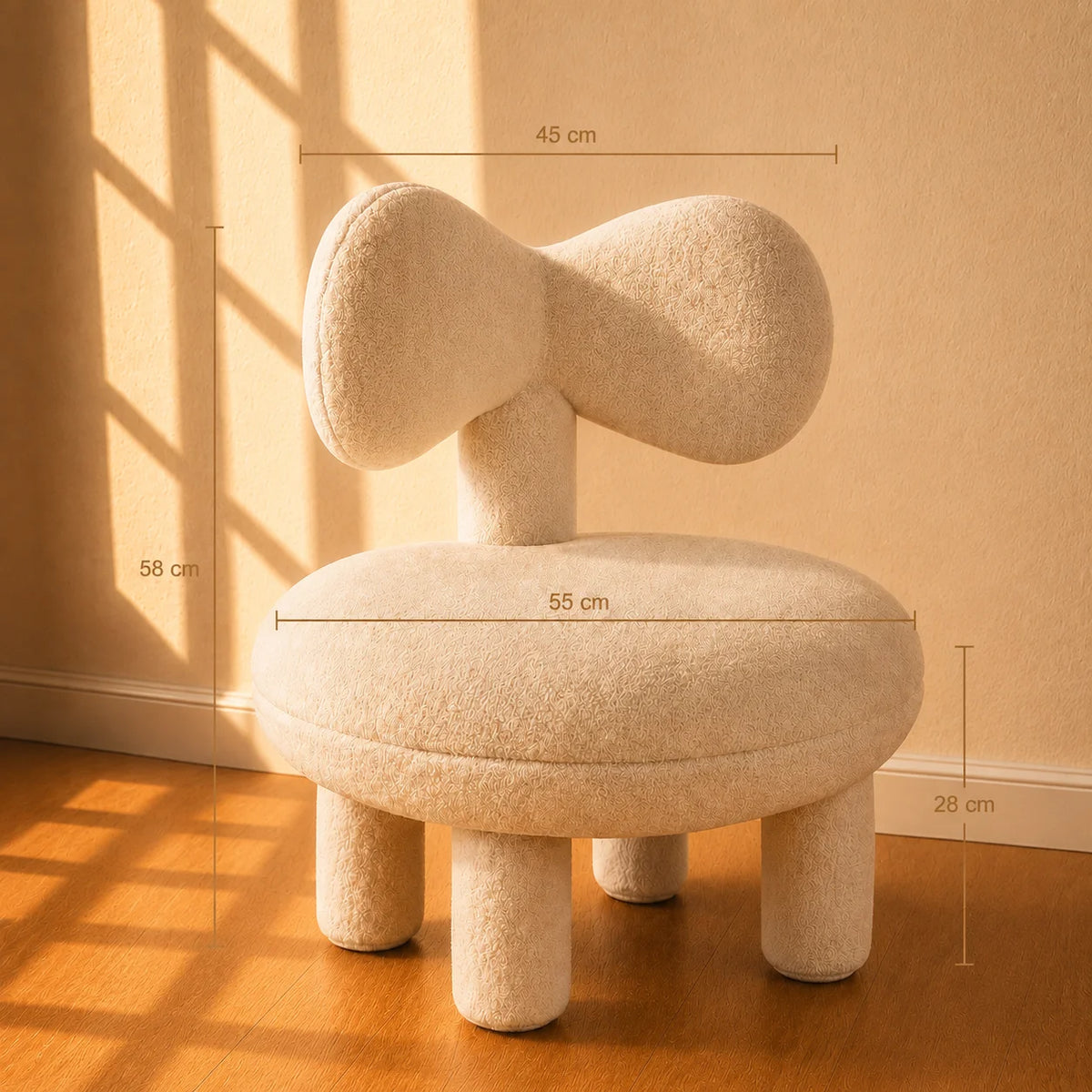 A small upholstered stool or chair with a rounded, organic-shaped backrest and four legs, shown in a warm sunlit room with overlaid dimension lines and labels (45 cm, 58 cm, 55 cm, 28 cm). The product appears in a real interior setting with wall, baseboard, and wood floor visible, so this is Lifestyle rather than Product/Packaging.