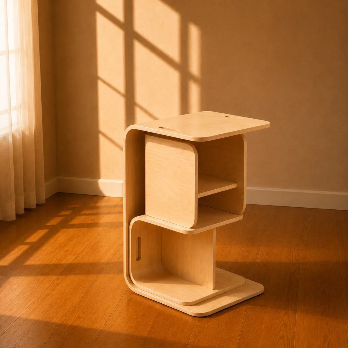 A light natural wood modular side table or organizer with curved plywood edges, shown in a warm sunlit room with wood flooring and a beige wall.