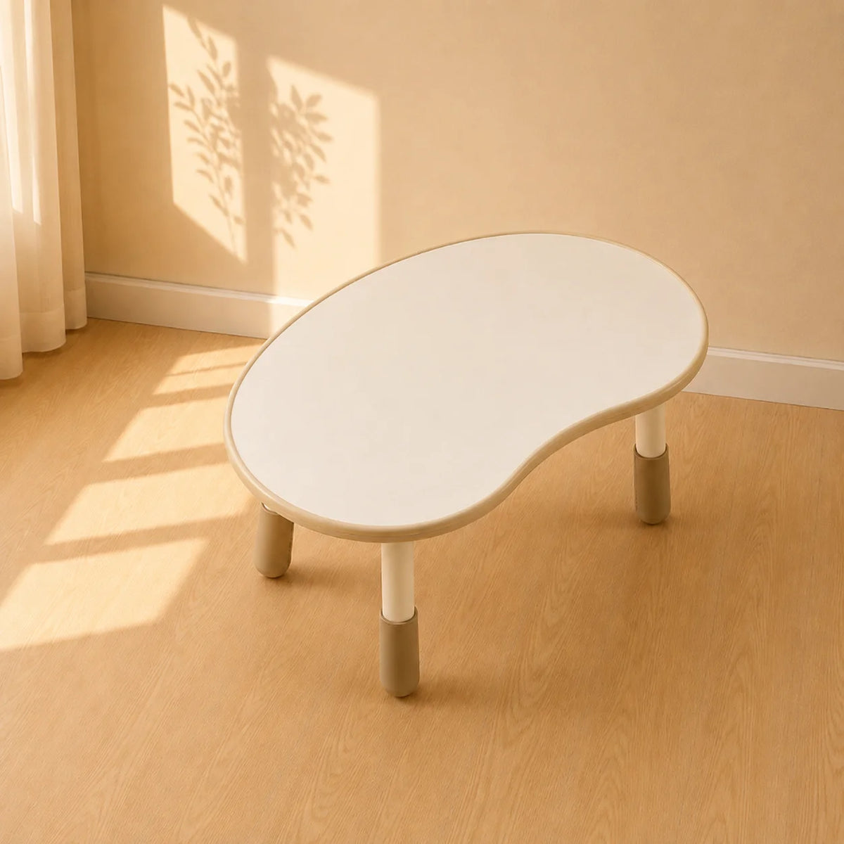 A small kidney-shaped white table with tapered legs and gray protective caps, shown on a light wood floor against a beige wall.