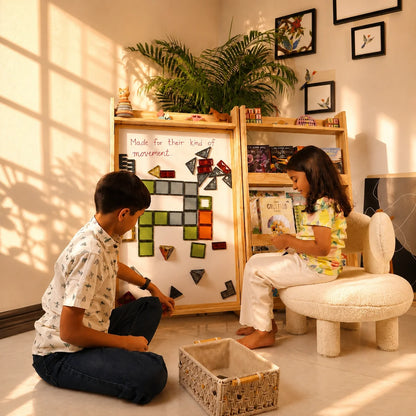 A light natural wood shoe organizer with a slanted top and multiple cubby compartments, shown in a warm, sunlit room with a wooden floor and beige wall.