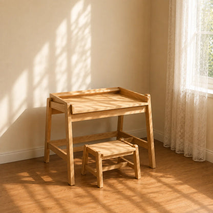 A young girl sits at a light natural wood children's desk with a matching stool, drawing in a sunlit room with warm wood floors and cream walls.