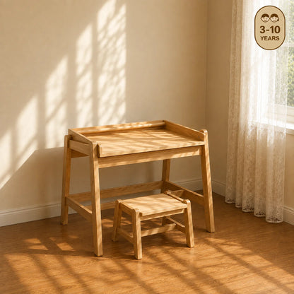 A light natural wood children's activity table with a matching step stool in a sunlit room with hardwood floors, sheer curtains, and framed animal prints on the wall. A circular badge in the top right reads '3-10 YEARS'.